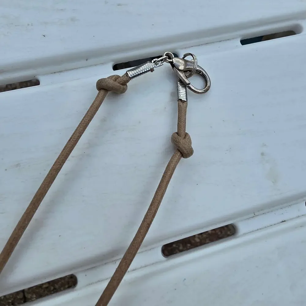beige leather cord necklace with a silver-tone ring pendant